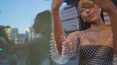 Uzun saçlı esmer, kentsel cam arka planda kendi fotoğrafını çekiyor. Afro-Amerikalı kız elinde kahve fincanıyla akıllı telefondan fotoğraf çekiyor. Modern şehirde rahatlayan güzel bir kadın. 