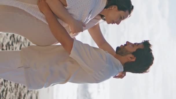 家人期待着宝宝在美丽的海滨亲吻阳光明媚的周末垂直方向靠近 怀孕的妻子抱着心爱的丈夫在沙滩上享受暑假 快乐怀孕的概念 — 图库视频影像