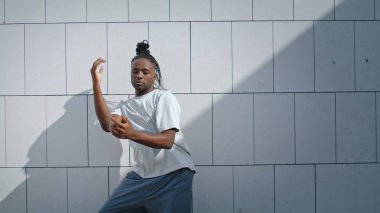 Şehirde koreografi pratiği yapan esnek bir dansçı. Dreadlocks sanatçısı şehir merkezinde modern dans eğitimi performansı sergiliyor. Beyaz duvar arka planında serbest dans eden Afrikalı Amerikalı adam..