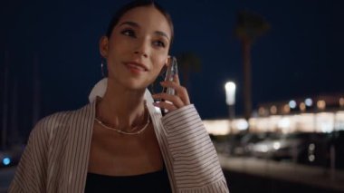 Gece vakti cep telefonuna cevap veren mutlu bir kadın. Açık havada akıllı telefon sohbetinden keyif alan rahat ve çekici bir kızın portresi. Modayı takip eden bir bayan cep telefonuyla konuşuyor.