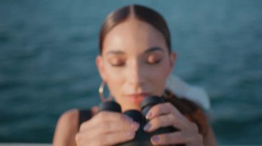 Dürbünlü bir kadın yaz tatilinde okyanus manzarası seyrediyor. Güneşli deniz manzarasının keyfini çıkarırken gülümseyen çekici, rahat kız gezginin portresi. Muhteşem dişi turist, deniz güzelliğini düşünüyor..