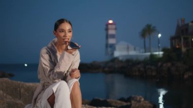 Alacakaranlık rıhtımında dinlenen akıllı telefondan gülen kız sesli mesaj kaydediyor. Gülümseyen kadın turist rıhtımda ses bildirimi yaratıyor. Kaygısız kız iletişim için cep telefonunu kullanıyor..