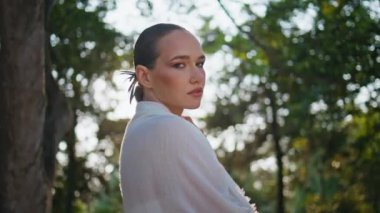 Sakin kız güneşli hafta sonlarında doğanın tadını çıkarıyor. Ormanda parlak güneş ışığına bakan, gerçekten rahat bir kadın. Yeşil güzel parkta poz veren muhteşem bir model. Güzellik konsepti