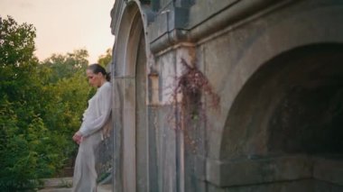 Eski mimaride dinlenen kadın eski duvara yaslanıyor. Terasta beyaz takım elbiseli, terk edilmiş bir kalede duran zarif genç bir kadın. Ortaçağ sarayında poz veren muhteşem, rahat kız..