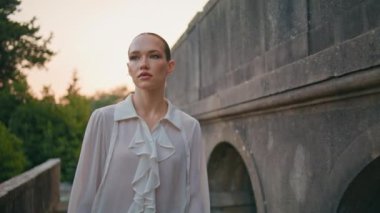 Sakin bir kadın, yaz akşamları ortaçağ binasında geziniyor. Kapatın. Antik mimaride yürüyüp tatilin tadını çıkaran rahat çekici bir kız. Beyaz gömlekli güzel bayan eski kaleyi keşfediyor..