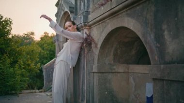 Eski duvarlara yaslanmış antik binada poz veren muhteşem bir model. Ortaçağ şatosuna bakan kendine güvenen güzel bir kadın. Terk edilmiş beyaz takım elbiseli şık bir model dışarıda duruyor..