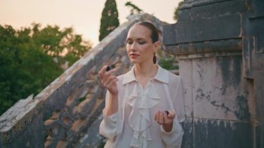 Dışarıdaki eski bina merdivenlerinde böğürtlen kokusundan hoşlanan romantik bir kadın. Rahatlamış çekici kız parmaklarda aromatik vitamin böğürtlenini kokluyor. Sakin model bir avuç organik böğürtlen.