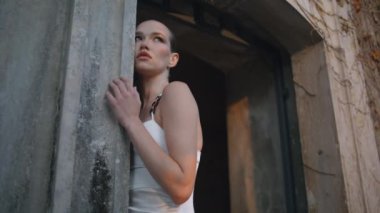 Şatafatlı bir kadın sonbahar akşamı eski bir ortaçağ binasına dokunuyor. Eski bir şatonun kemerinde kameraya bakan gösterişli bir kadın. Terk edilmiş sarayda poz veren beyaz elbiseli muhteşem bir manken.