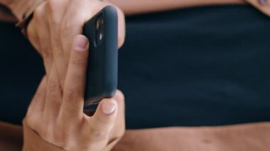 Parkta akıllı telefondan mesaj atan erkek parmakları dikey olarak kapatıyor. İlkbahar doğasında modern bir cihaz kullanarak sıradan bir iş adamı mesajı yazıyor. Cep telefonunda çalışan bilinmeyen bir adam. İletişim konsepti 
