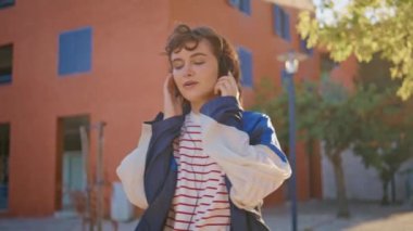 Sunny caddesinde müzik dinlemekten hoşlanan genç bir meloman. Kıvırcık, rahat bir kadın en sevdiği şarkıyı dinliyordu. Kulaklıklı çekici kız dışarıda dinleniyor..