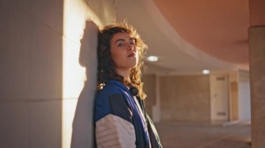 Şehir kızı güneş ışığı altında şehir binasına yaslanmış sakız çiğniyor. Akşam ışıklarında poz veren romantik kıvırcık kadın dışarıda kameraya bakıyor. Modayı takip eden gençler hafta sonunun tadını çıkarıyor..