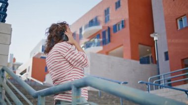 Retro kız, şehir korkuluklarına dayanan kulaklıklarla müzik dinlemeyi sever. Rahatlamış kadın melomanyak sokak merdivenlerinde şarkı söylerken gülümsüyor. Tasasız genç kadın klasik kaset çalar kullanıyor..