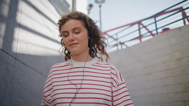 Modna Dziewczyna Słuchając Piosenki Słuchawce Spacerując Słoneczną Ulicę Blisko Zrelaksowana — Wideo stockowe