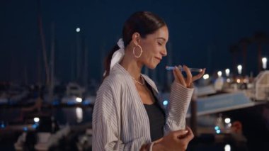 Kaygısız bayan, gece vakti rıhtım yakınlarında akıllı telefon mesajıyla ses kaydı yapıyor. Akşam iskelesinde cep telefonu hoparlörüyle konuşan gülümseyen esmer turist. Mutlu kadın rıhtımda dinleniyor