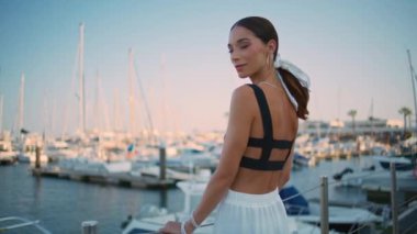Limanda demirli beyaz yatlarla poz veren hayalperest kadın yaz akşamı. Rıhtımda tek başına duran rahat, muhteşem bayan. Bronz tenli kadın gezgin hafta sonları deniz manzarası seyrediyor.
