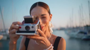 Kaygısız gezgin, deniz kenarını demirli yatlarla fotoğraflıyor. Yaz akşamını yakın. Rıhtımda fotoğraf makinesi merceğine bakan kaygısız, gülümseyen kadın. Muhteşem mutlu kız geçmişe dönük kamerayla fotoğraf çekiyor..