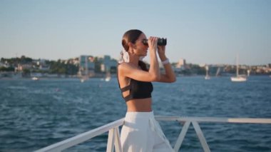 Dürbünlü kız yaz haftasonu okyanus manzarasının tadını çıkarıyor. Şık, lüks bir kadın tatil yolculuğunda deniz manzarasını izliyor. Deniz manzarasına bakan muhteşem bir bayan turist setin orada duruyor..