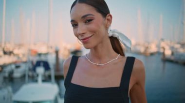 Lüks beyaz yatların önündeki kameralı turist görünümlü oyuncu kadın. Şık kıyafetler içinde güzel bir sette poz veren mutlu bir manken. Muhteşem kız okyanus rıhtımında durup tatilin tadını çıkarıyor.