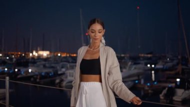 Yaz akşamı limanda duran zengin kız. Koyu deniz limanına demirlemiş yatlarda poz veren şık kıyafetli güzel bir bayan. Şatafatlı kadın alacakaranlıkta tek başına güzel bir rıhtımda dinleniyor..