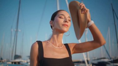 Modeller hasır şapkalarını çıkarıp güneşli seti kapatıyorlar. Lüks yatların yanında rıhtımda gezen mutlu, rahat bir kadın. Zarif muhteşem kız yaz gezintisinin tadını çıkarıyor. Bayan kaygısız tatilde dinleniyor..