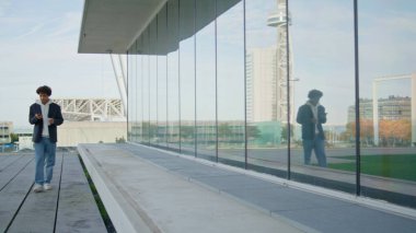 Rahat genç, kentte tek başına yürüyen cam yansıması. Kıvırcık saçlı öğrenci elinde kahve fincanıyla akıllı telefondan mesaj atıyor. Cep telefonu kullanan modern blogcu. Milenyum gençleri sakince şehir merkezine taşınıyor.