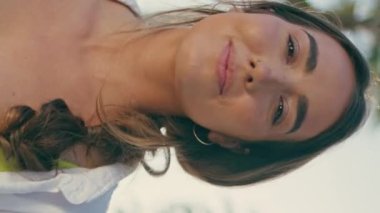 Neşeli kız dikey olarak tropikal caddeden geçiyor. Palmiye ağaçlarının arka sokaktaki portresine bakan mutlu, rahat bayan kamerası. Kaygısız kadın yazın keyfini çıkarıyor güneşli bir sokak tatili