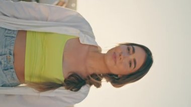 Gülümseyen kadın sokak dikey portresine poz veriyor. Beton stadyumun arka planında kız arkadaşını öpen mutlu milenyum çocuğu. Kendine güvenen kaykaycı yazın tadını çıkartıyor