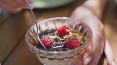Kadın elleri, kafeye yakın bir yerde cam tabaktan meyveli tatlı yiyor. Tanınmayan bir kadın tatlı karamel kremalı krema yiyor yaz restoranının terasında kremalı yemeğin tadını çıkarıyor. Yiyecek konsepti