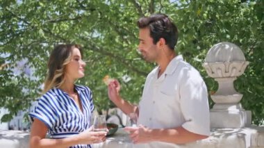 Sunshine Terrace 'da mutlu çift romantik buluşmalar. Yakın çekim. Sevgi dolu bir kadını yeşillikte besleyen yakışıklı İspanyol bir adam. Rahatlamış aşıklar yazın şampanya içerek gülüyorlar. Gözlüklü neşeli çift