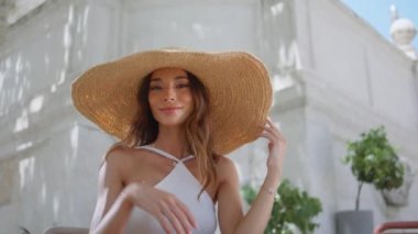Hasır şapkaya dokunan seksi bir kadın. Gün ışığında kafenin portresine gülümseyerek poz veriyor. Yazlık terasta kameraya bakan güzel, zarif bir kız. Mutlu, muhteşem esmer, yüzünü kaplayan yalnız başına rahatlayan.