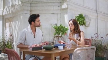 Teras restoranında yemek paylaşan rahat bir çift. Modern tarz kafede lezzetli yemekler yiyen güzel bir çift. İki insan hafta sonu haberleri tartışarak yemek tadıyor.