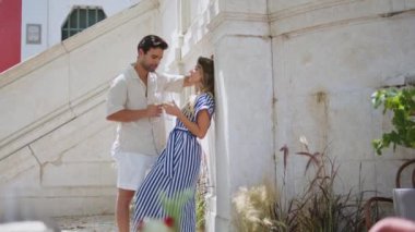 Sevgili çift romantik balayı tatilinde birlikte beyaz şarap içer. Balkonda yıldönümü kutlamalarında gözlük tutan neşeli aşıklar. Mutlu sevgili nazikçe konuşuyor. Aşk konsepti 
