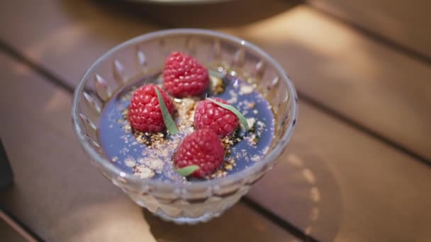 クローズアップベリーは夏のカフェでデザートプレートをムースにします 木のテーブルで提供するおいしい甘い食べ物 おいしいレストランディナーのためのフルーツケーキピース テーブルウェアの部分 グルメペストリーコンセプト — ストック動画
