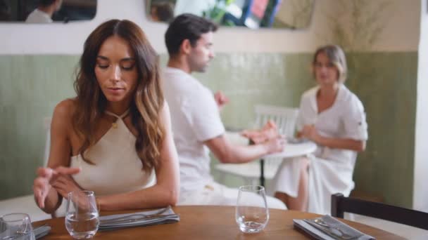 单身妇女在咖啡店的特写镜头边喝水 沮丧的悲伤的女士在舒适的餐厅里孤独地喝着水 不幸的黑发女孩在失败的约会中等男朋友 伤心欲绝的模型 — 图库视频影像
