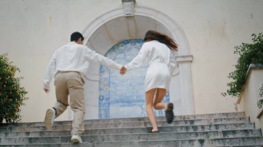 Merdivenlerde koşan heyecanlı aşıklar. Pozitif kadın, Azulejo duvarında el ele tutuşurken eğleniyor. Neşeli sevgililer eski mimaride birlikte gülerek basamakları tırmanıyor. Mutlu çiftler. 