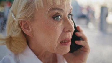 Kapalı yerde sinirli bir emeklinin akıllı telefonu araması dışarıda negatif duyguları ifade ediyor. Sinirli yaşlı iş kadını cep telefonuyla tartışıyor. Tatmin olmamış iş sorunu. Yaşlı kadın cep telefonundan bağırıyor..