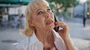 Şehir caddesinde cep telefonundan konuşan emekli bir bayan. Kapatın. Olumlu yaşlı bir kadının akıllı telefonu arayarak dışarıdaki arkadaşlarıyla konuştuğu portresi. Zarif emeklinin cep telefonu konuşmasına göre düzeni sağlaması.