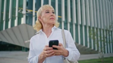 Akıllı telefonlu yaşlı bir kadın şehir sokağında toplanmayı bekliyor. Cep telefonuyla gezen zarif yaşlı bir bayan açık havada mobil harita uygulaması kullanıyor. Başarılı iş kadını telefon ekranı arıyor