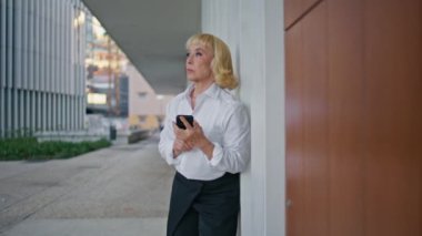Yaşlı iş kadını toplantı bekliyor. Elinde akıllı telefonuyla caddeyi yakınlaştırıyor. Şehir merkezinde cep telefonu gözetleyen zarif, yaşlı bir kadın. Dışarıda cep telefonundan mesaj okuyan ciddi bir yaşlı kadın.
