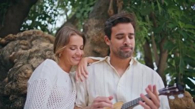 Sevecen aşıklar yeşil doğada gitar müziği dinlendiriyorlar. Büyük Ağaç Parkı 'nda şarkı söyleyen kadını seven adam. Ukulele tutan yakışıklı, traşsız adam kız arkadaşıyla rahatlıyor. Aşk çifti romantik randevu