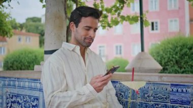Maço 'nun şehir parkında akıllı telefondan randevu beklemesi çok güzel. Mavi fayans dükkanında tek başına dikilen gülümseyen İspanyol cep telefonu konuşuyor. Yakışıklı esmer, dışarıda cep telefonu kullanıyor.