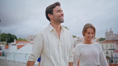 Romantik yeni evliler şehir manzarası olan terasta yürüyorlar. Yakışıklı esmer beyefendi Akdeniz 'de gülümseyen kız arkadaş elini öpüyor. Rahatlamış mutlu çift birlikte gülerken manzarayı seyrediyor.
