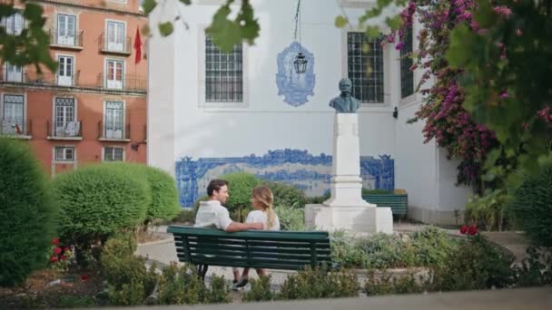 都会の公園でベンチに座っているカップルが大好きです ロマンチックなデートで一緒に時間を楽しむガールフレンドを抱擁する愛情深い男 緑の自然の中で愛らしいペアリング ハネムーン バケーション コンセプト — ストック動画