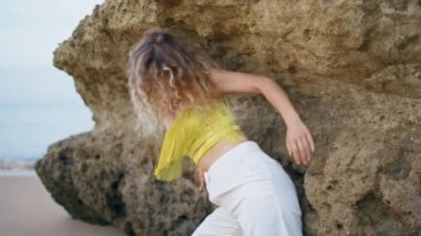 Rock Shore 'da çağdaş dansçı şehvetli danslar yapıyor. Genç kıvırcık kadın sahilde zarif vücut hareketleri yapıyor. Doğada modern koreografi pratiği yapan esinlenmiş kız dansçı..