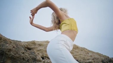 Esnek kız vücudu mavi gökyüzünde şehvetle hareket ediyor. Yaklaş. İlham verici profesyonel dansçı yaz doğası üzerine çağdaş bir performans sergiliyor. Yetenekli kadın sanatçı dans doğaçlaması yapıyor..