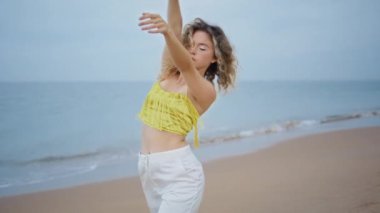 Havalı dansçı kadın, Sandy Beach 'te son moda kıyafetlerle serbest dans ediyor. Profesyonel kadın sanatçı, akşam deniz kıyısında modern koreografiyi gösteriyor. Çekici kız dansçı..