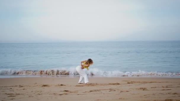 美しい砂浜で即興演奏する少女ダンサー センセーショナルな女性振付師が 嵐のような海の波で踊っています 夜の海岸線に柔軟なボディを移動するプロフェッショナルな女性パフォーマー — ストック動画