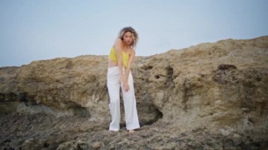 Kıvırcık kız, yaz akşamları kum kayasında dans ediyor. Esnek, genç bir kadın. Vücudunu hareket ettiriyor. Sakin doğanın tadını çıkarıyor. Profesyonel dansçı, taşlı arazide çağdaş bir tarz sergiliyor..