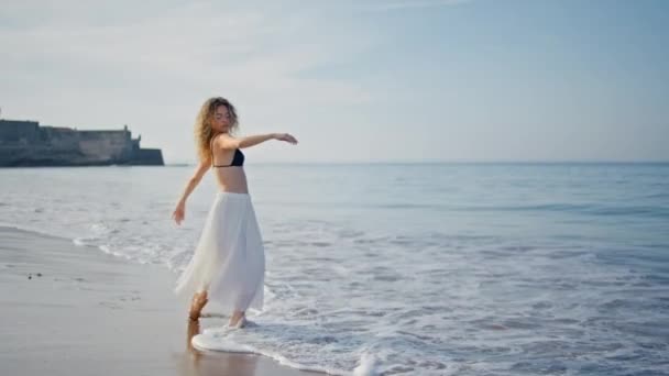 海の波の夏の朝に現代の振付を練習するパフォーマー 海水で踊る感覚的なカーリーな女性が脚で飛び散ります 日当たりの良いビーチで優雅に動くテンダーガールダンサー — ストック動画