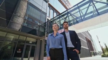 Çağdaş ofis binasının dışındaki portre çifti ofis çalışanları yakınlaştırsın. Güneşli şehir sokağında birlikte poz veren kendine güvenen iki iş ortağı. Birkaç şirket yöneticisi modern şehir merkezinde duruyor.